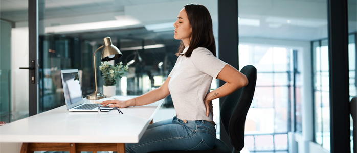 a woman sitting at a desk with back pain